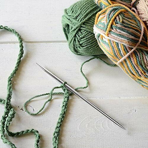 Knitting needle with green and multicolored yarn on a wooden surface.